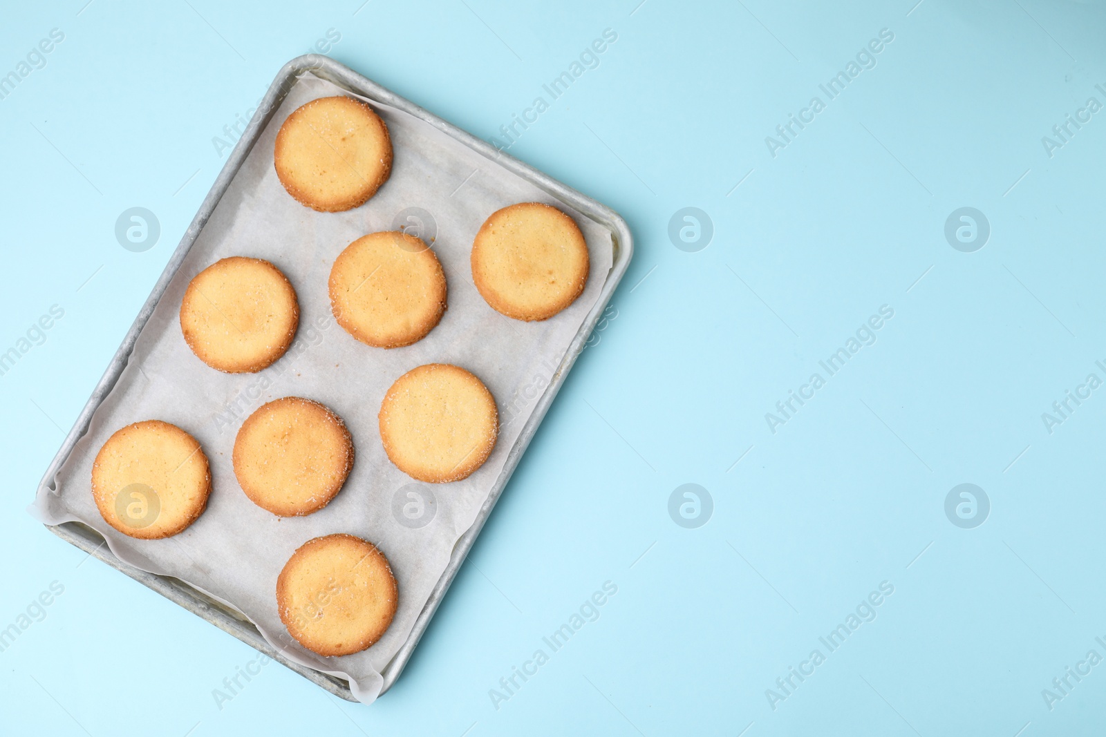 Photo of Tray with tasty sweet sugar cookies on light blue background, top view. Space for text