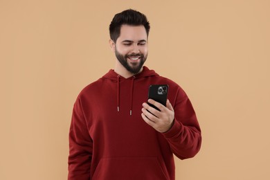 Photo of Happy young man using smartphone on beige background