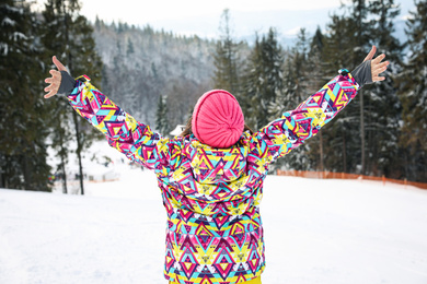 Photo of Young woman at mountain resort, back view. Winter vacation