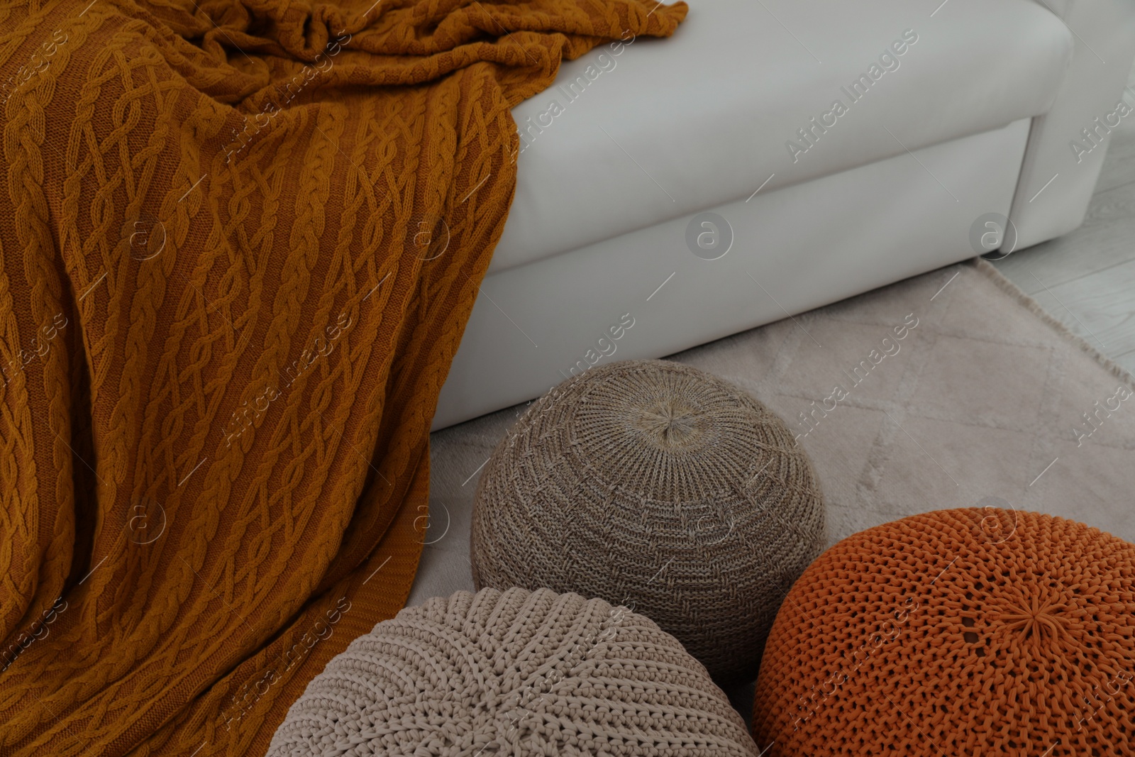 Photo of Different stylish poufs near white sofa in living room. Interior design