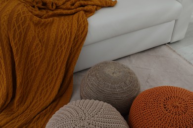 Different stylish poufs near white sofa in living room. Interior design