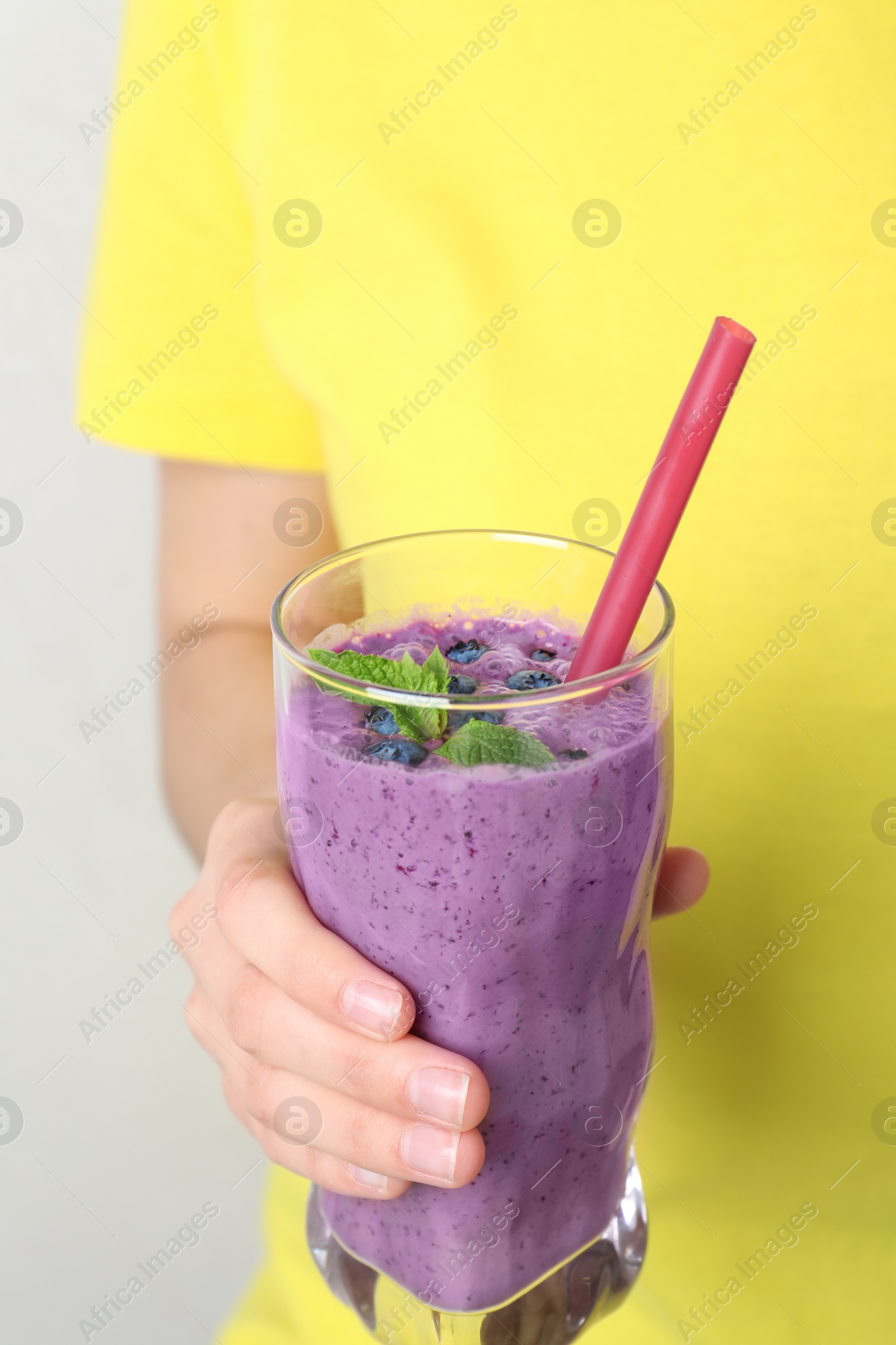 Photo of Woman holding glass of delicious blueberry smoothie, closeup