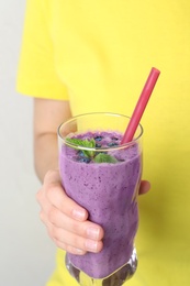 Woman holding glass of delicious blueberry smoothie, closeup