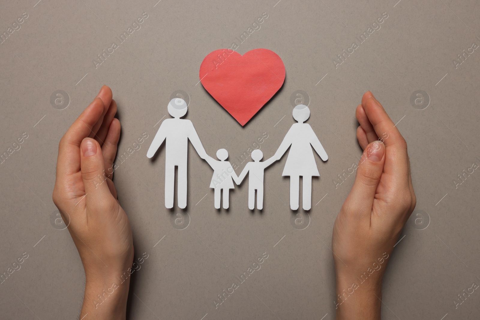 Photo of Woman protecting paper family figures and red heart on light grey background, top view. Insurance concept