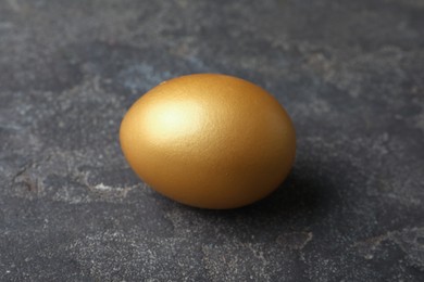 Photo of Golden egg on black table, closeup view