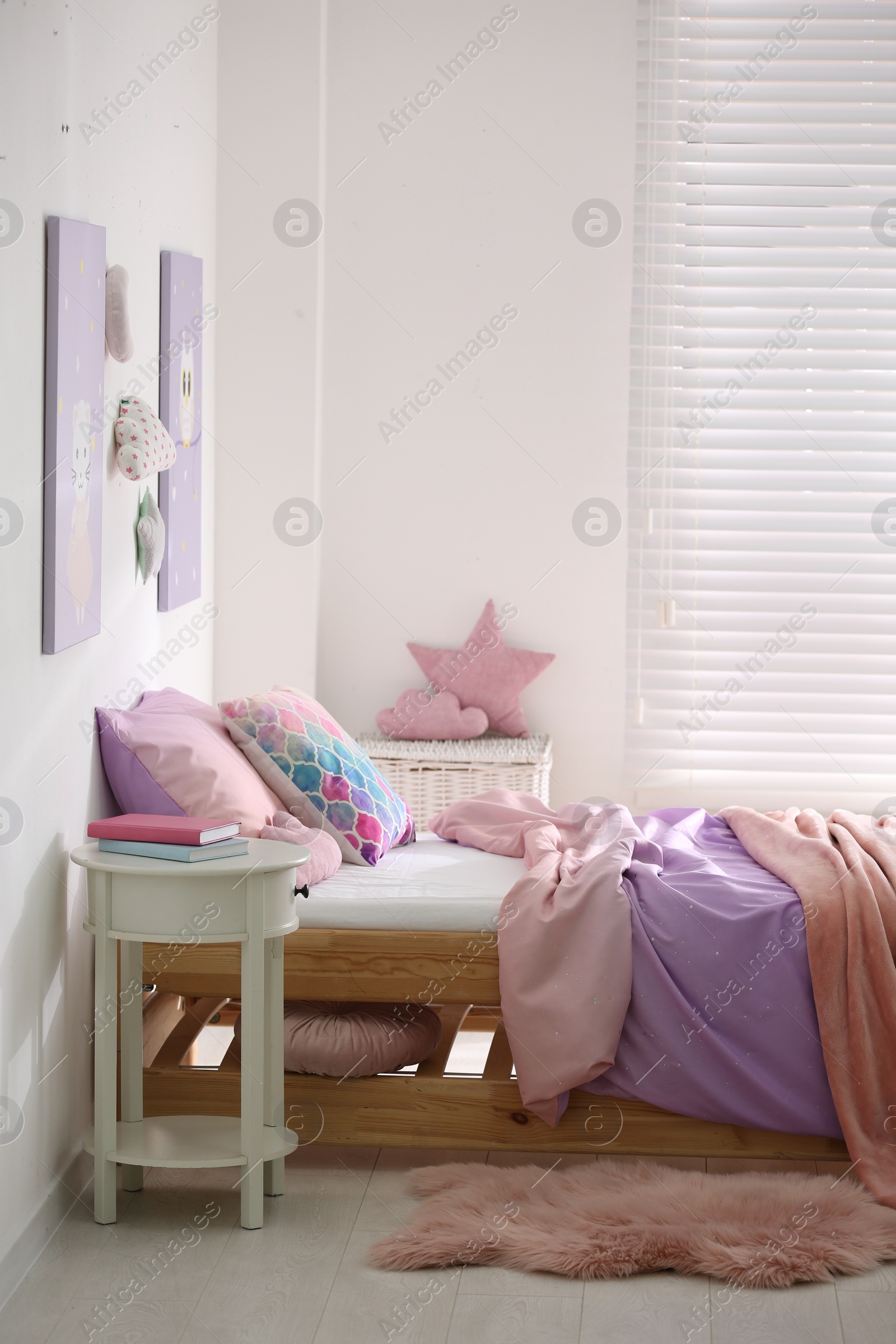 Photo of Bed with colorful linen in stylish children's room. Interior design