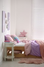 Photo of Bed with colorful linen in stylish children's room. Interior design