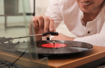 Photo of Happy man using turntable at home, closeup