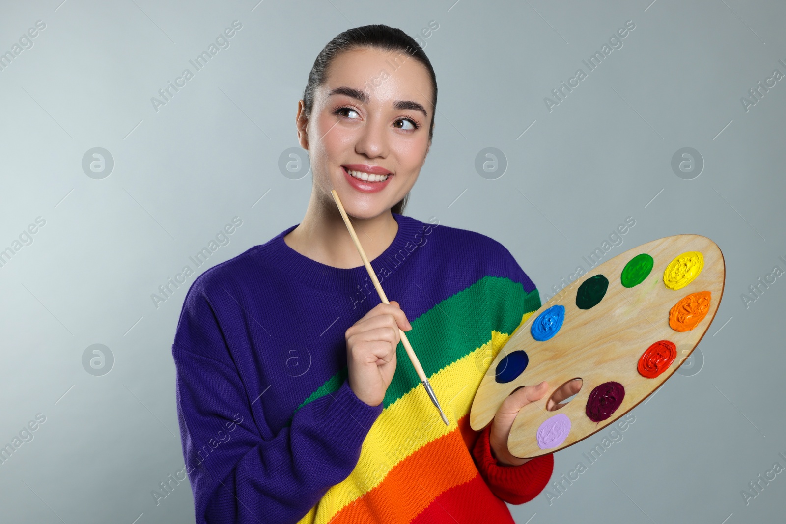 Photo of Woman with painting tools on grey background. Young artist