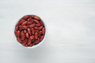 Photo of Bowl of canned kidney beans on white wooden table, top view. Space for text