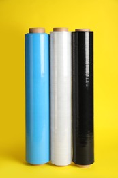 Photo of Rolls of different stretch wrap on yellow background