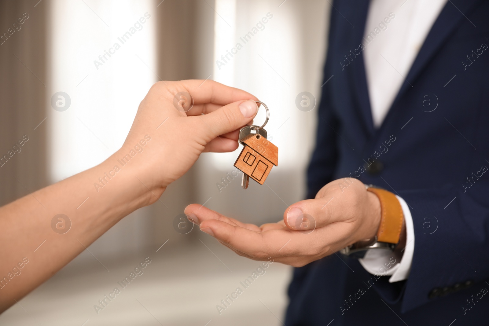 Photo of Real estate agent giving key with trinket to client in office, closeup