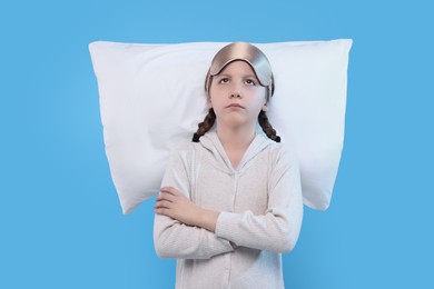 Photo of Girl with sleep mask and pillow on light blue background. Insomnia problem