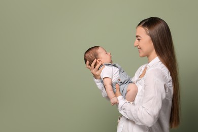 Mother holding her cute newborn baby on olive background, space for text