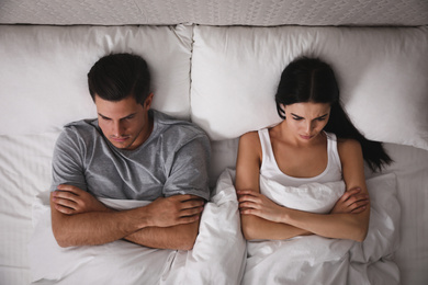 Photo of Couple with relationship problems in bed at home, top view