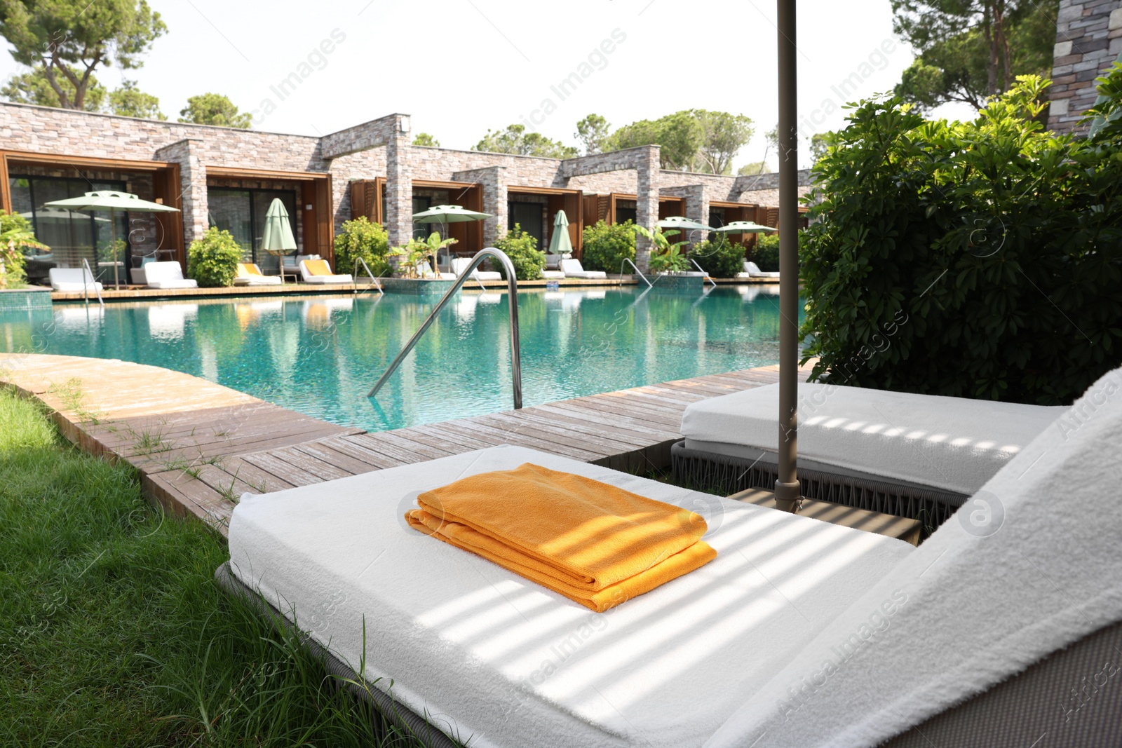 Photo of Sunbeds near outdoor swimming pool at luxury resort