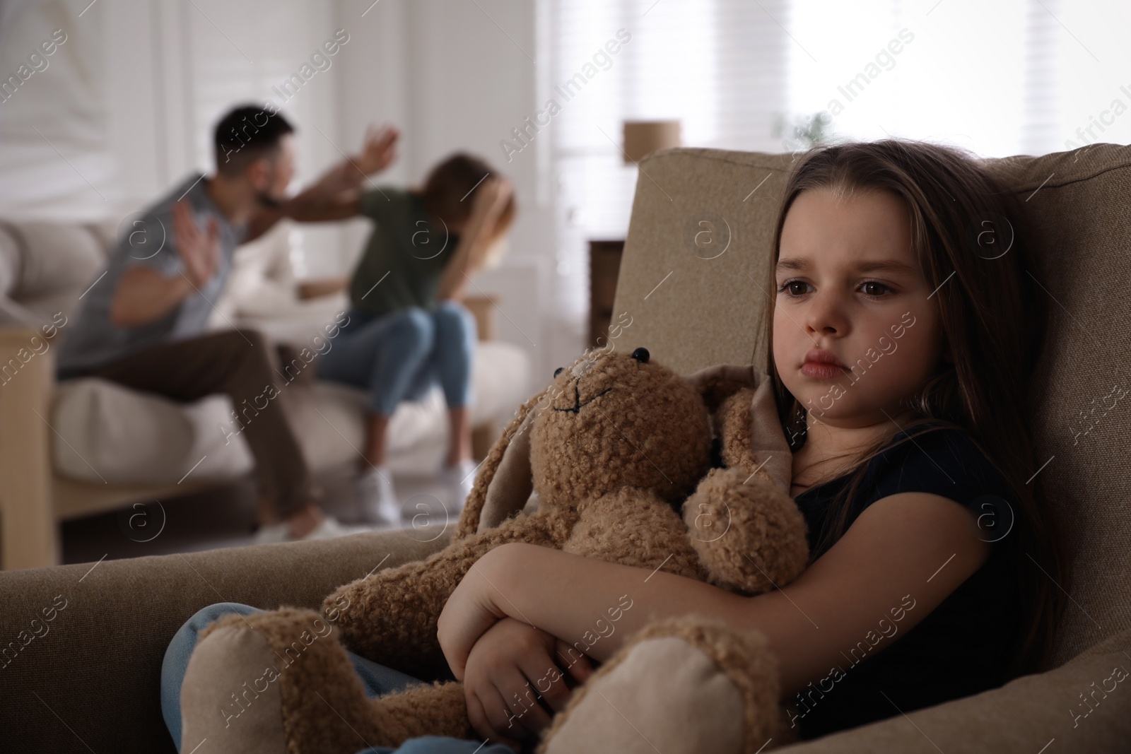 Photo of Couple fighting at home, focus on their unhappy little daughter. Domestic violence