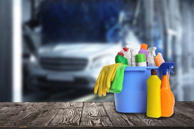 Image of Bucket with cleaning supplies on wooden surface at car wash. Space for text