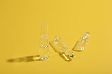 Glass ampoules with liquid on yellow background