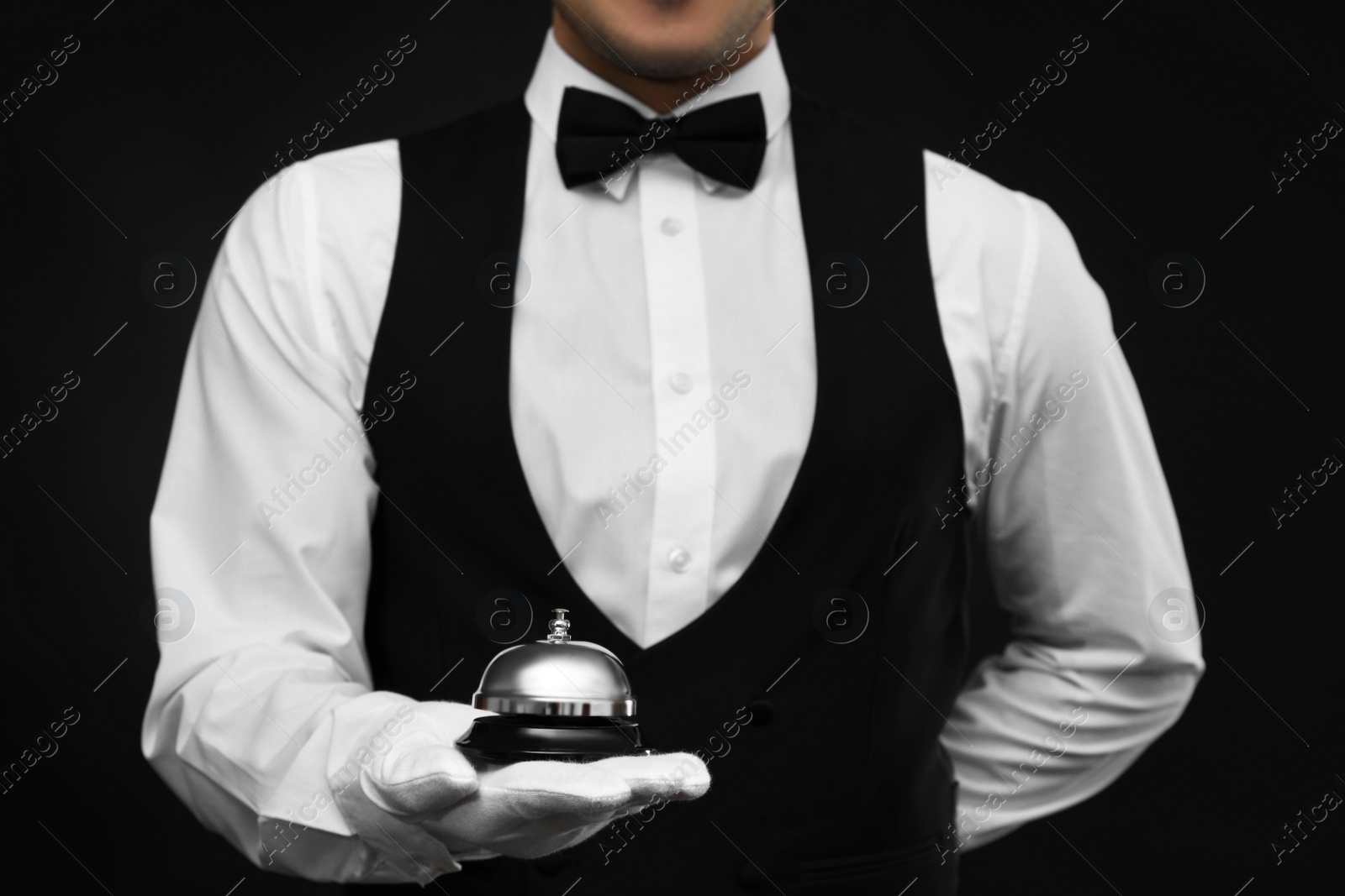 Photo of Butler holding service bell on black background, closeup