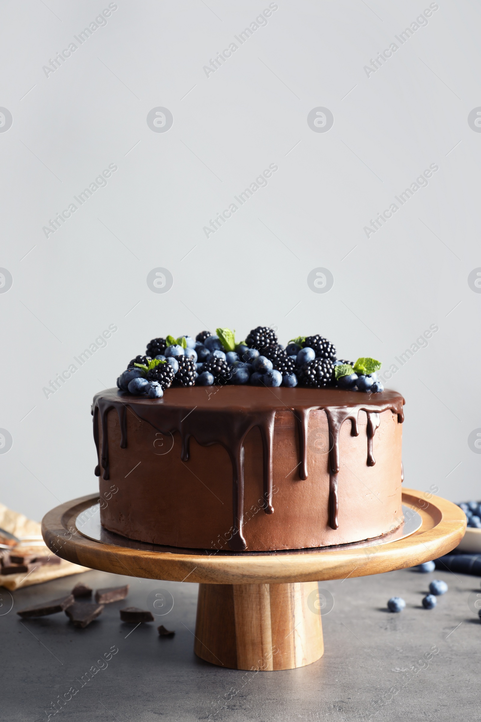 Photo of Fresh delicious homemade chocolate cake with berries on table against gray background