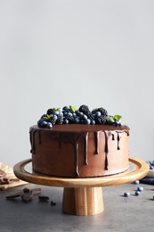 Photo of Fresh delicious homemade chocolate cake with berries on table against gray background