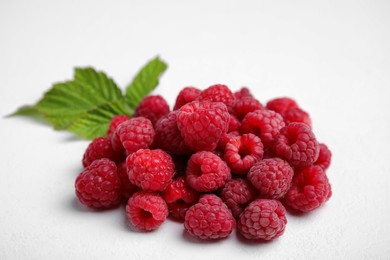 Photo of Fresh red ripe raspberries with green leaves on white background