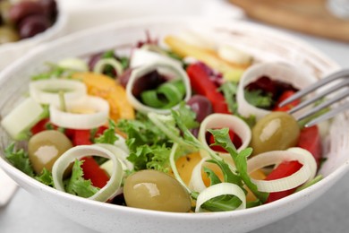 Bowl of tasty salad with leek and olives on table, closeup