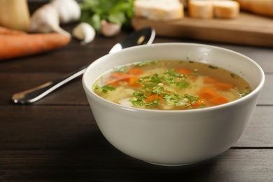 Photo of Bowl with fresh homemade chicken soup on wooden table