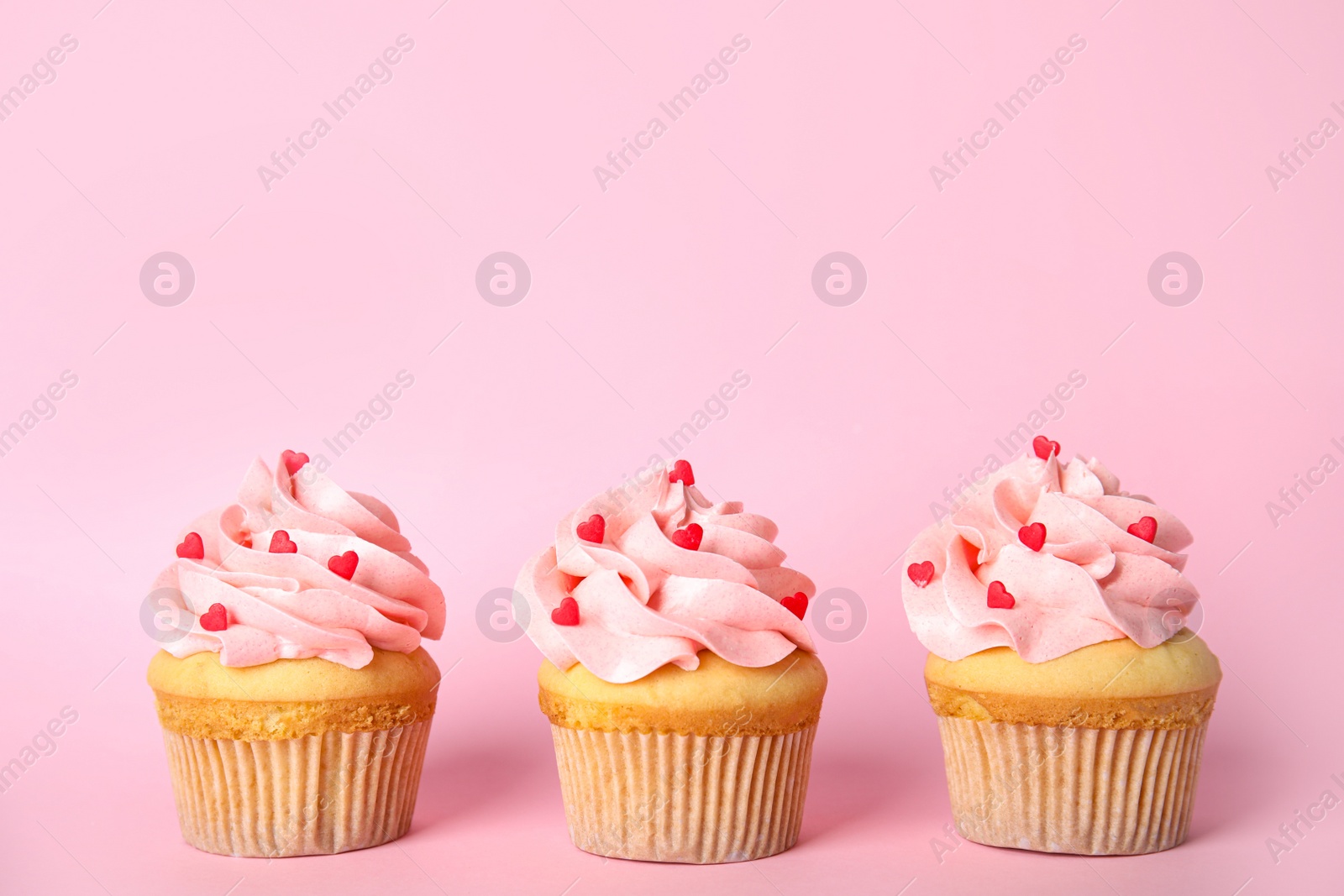 Photo of Row of tasty cupcakes on pink background, space for text. Valentine's Day celebration