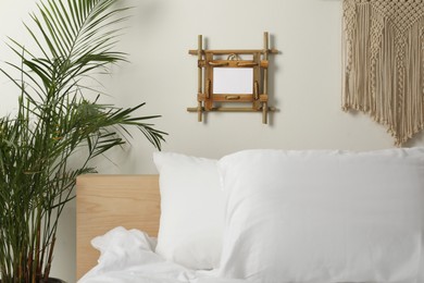 Photo of Empty bamboo frame hanging on white wall in bedroom
