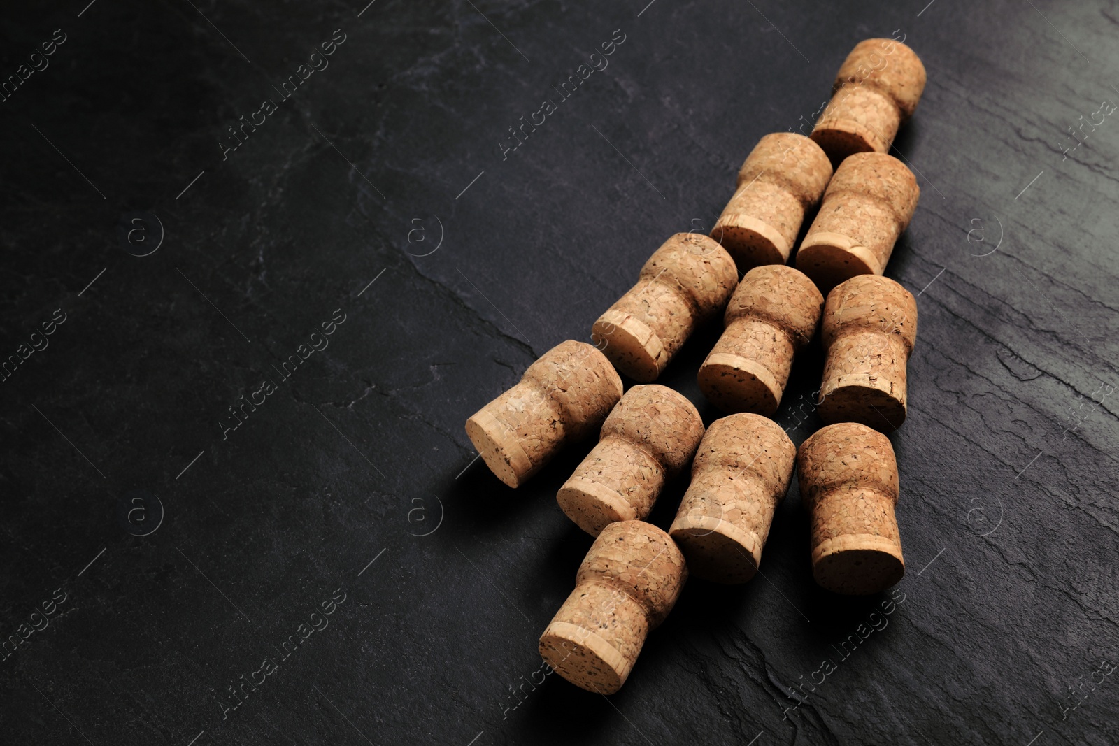 Photo of Christmas tree made of wine corks on dark stone background. Space for text