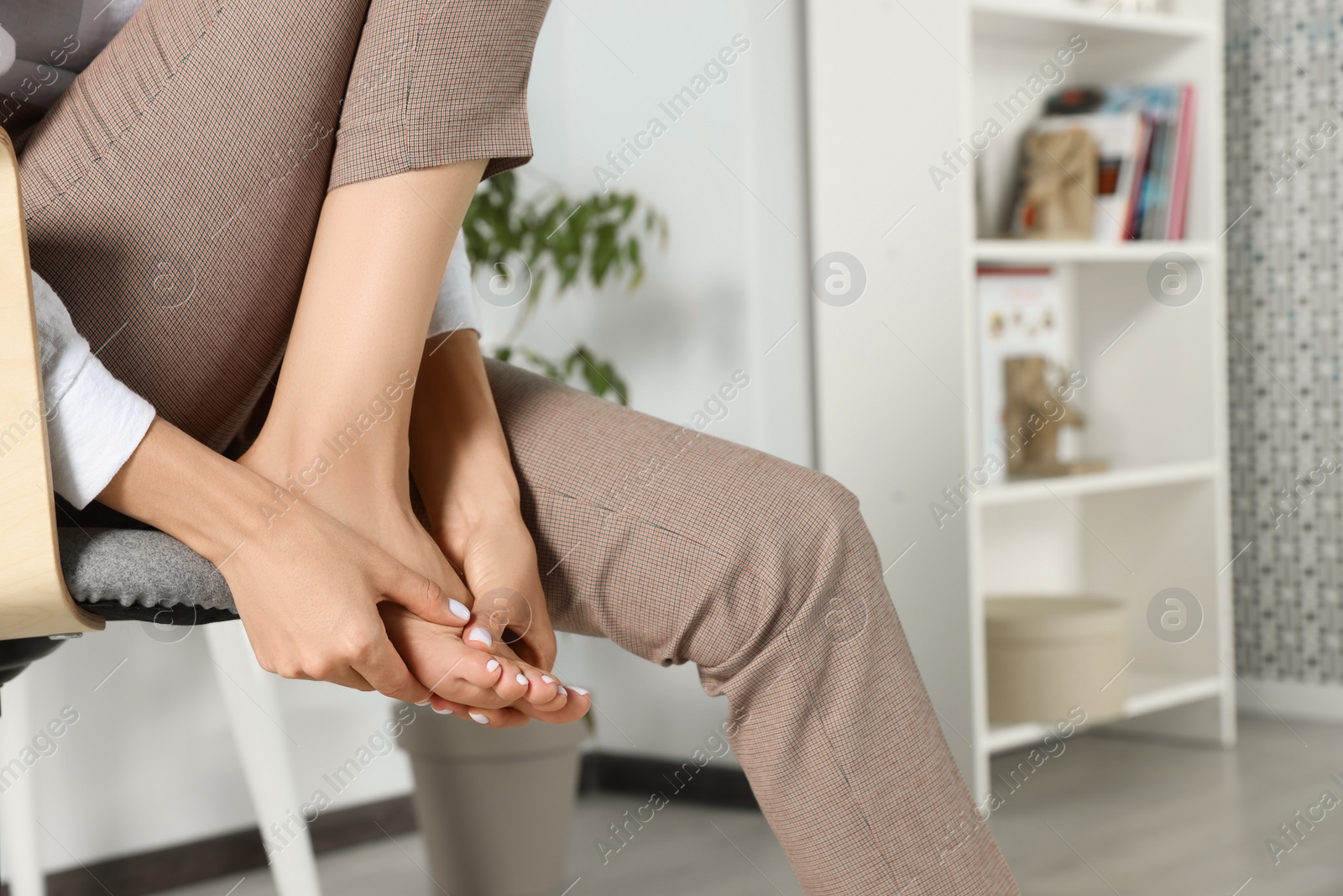 Photo of Woman rubbing sore foot at home, closeup. Space for text