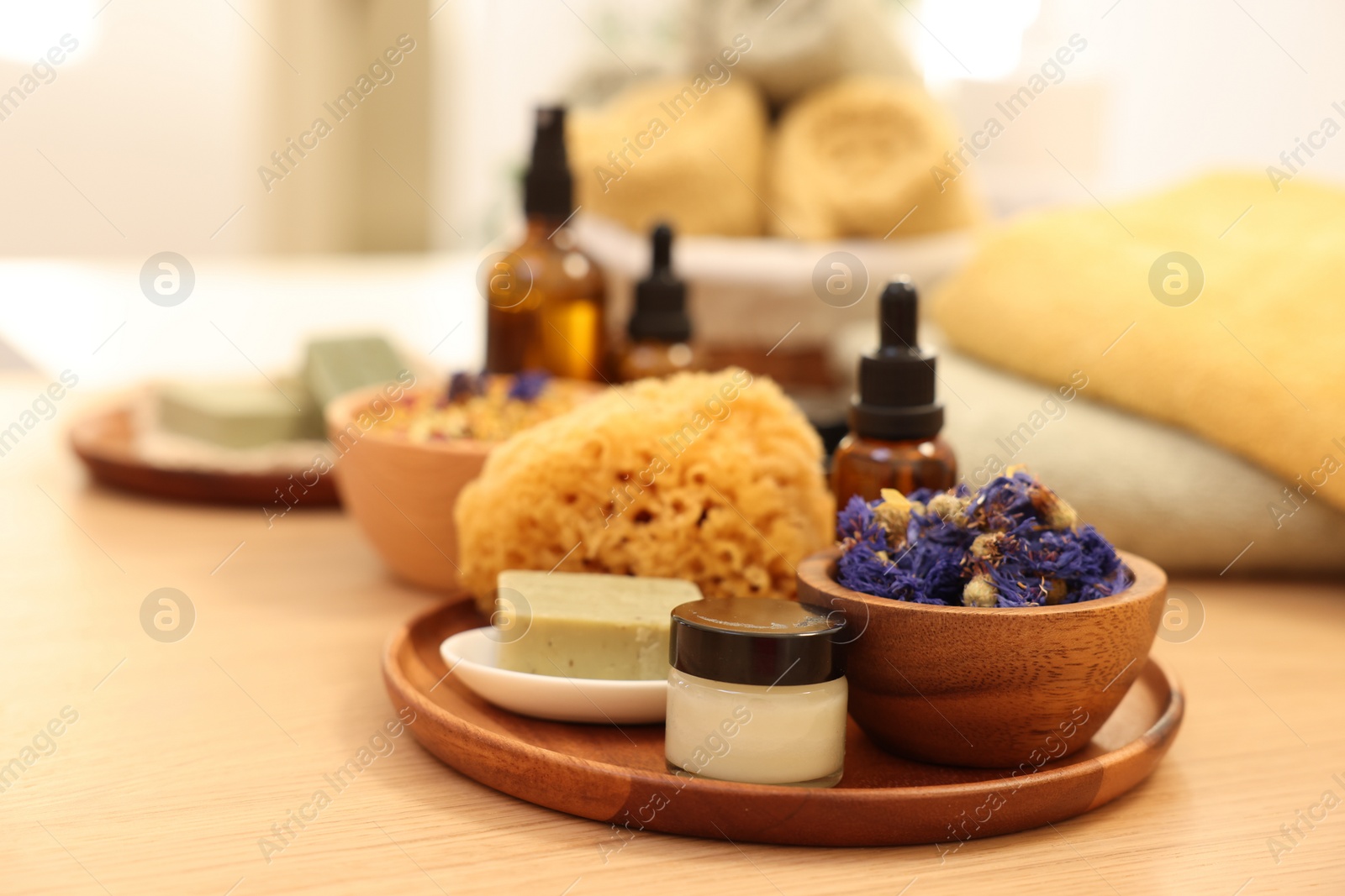 Photo of Dry flowers, loofah, soap bar, bottle of essential oil and jar with cream on wooden table indoors. Spa time