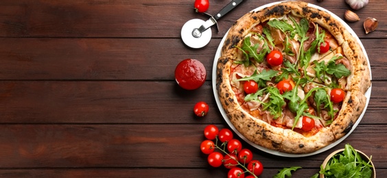 Photo of Tasty pizza with meat and arugula on wooden table, flat lay. Space for text