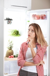 Woman choosing food from fridge at kitchen. Healthy diet