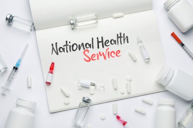 Image of National health service (NHS). Notebook with text and medications on white background, flat lay