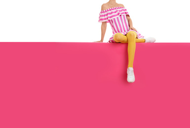 Woman wearing yellow tights and stylish shoes sitting on color background, closeup