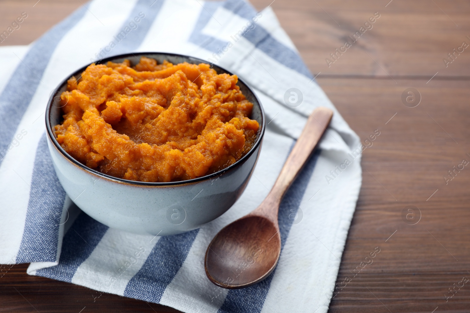 Photo of Bowl with tasty puree served on wooden table