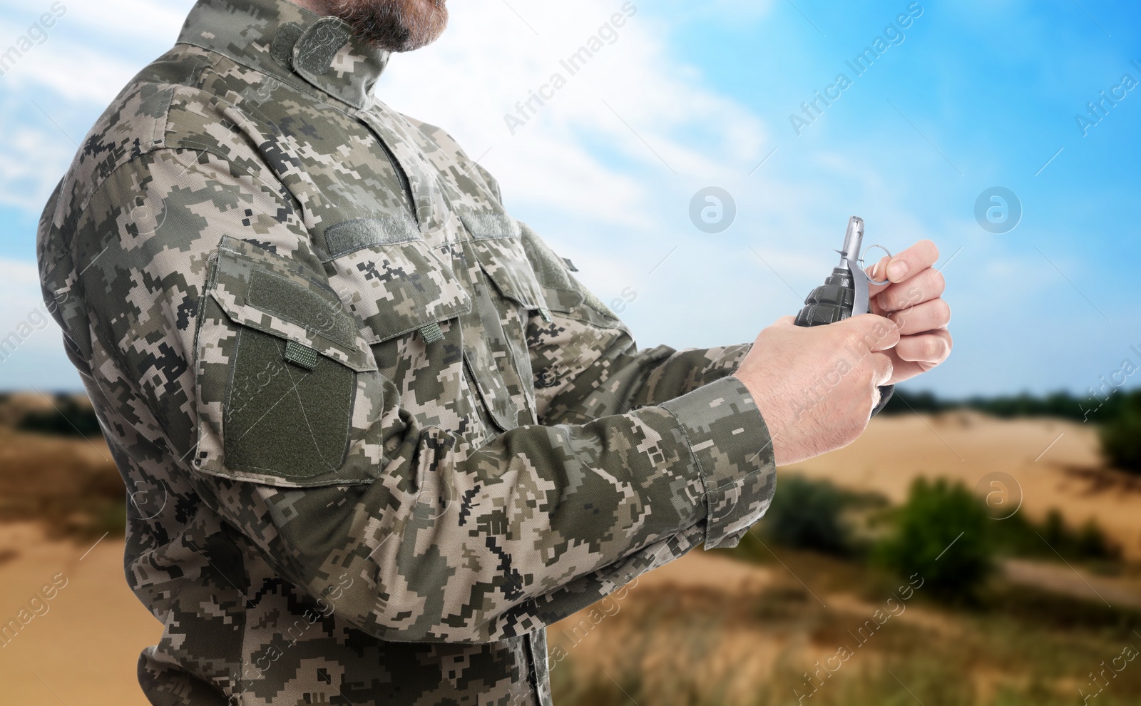 Image of Soldier pulling safety pin out of hand grenade outdoors, closeup