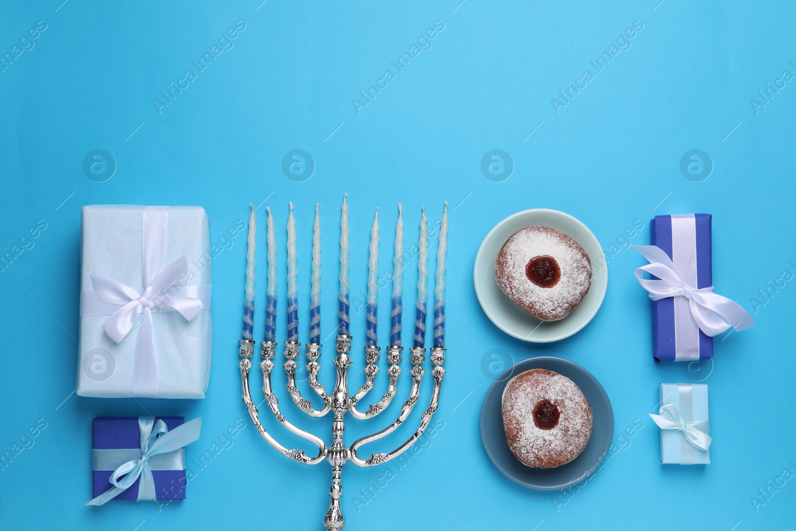 Photo of Flat lay composition with Hanukkah menorah and donuts on light blue background, space for text