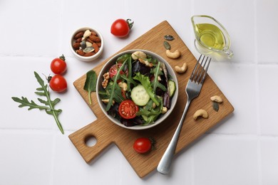 Tasty fresh vegetarian salad and ingredients on white tiled table, flat lay