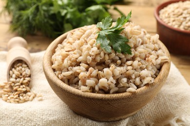 Photo of Delicious pearl barley with parsley in bowl on table, closeup