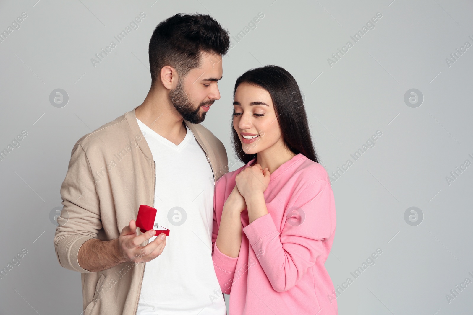 Photo of Man with engagement ring making marriage proposal to girlfriend on light grey background