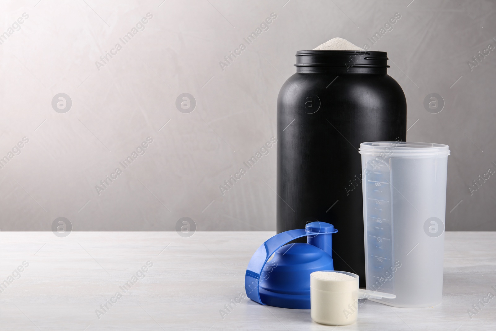 Photo of Composition with measuring scoop of protein powder on white table. Space for text