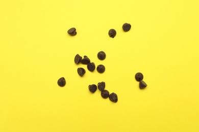 Photo of Delicious chocolate chips on yellow background, top view