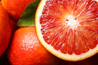 Photo of Whole and cut ripe red oranges with green leaf, closeup