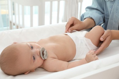 Mother changing her baby's diaper on table at home