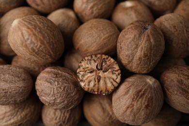 Photo of Whole and cut nutmegs as background, top view