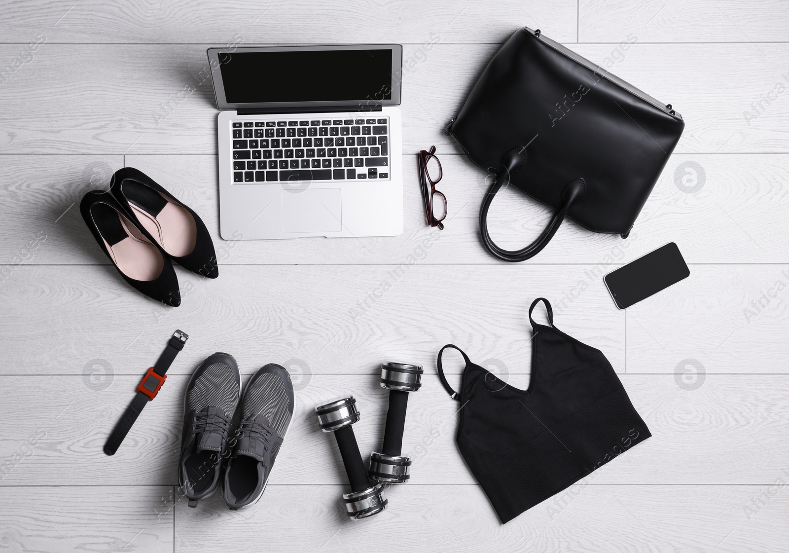 Photo of Flat lay composition with business supplies and sport equipment on white wooden floor. Concept of balance between work and life